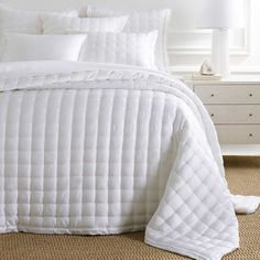 a bed with white comforters and pillows on it