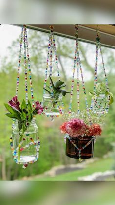 three hanging vases filled with flowers on a window sill