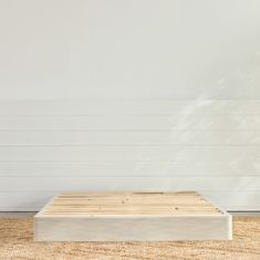 a wooden platform on the floor in front of a white wall and wood planks