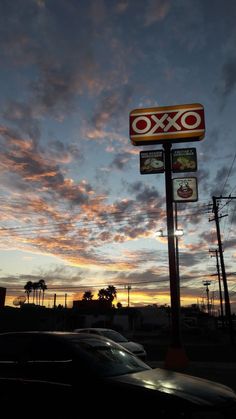 the sky is pink and orange as the sun sets over a restaurant sign in an urban setting