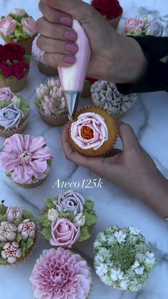 someone is decorating cupcakes with flowers and icing