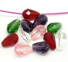 several different colored glass beads on a white surface with a pink cord in the background