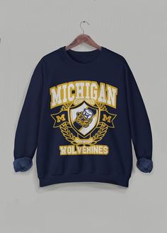 Vintage Michigan Sweatshirt, University of Michigan Crewneck, Retro Varsity Long Sleeve Sweater, Michigan University Wolverines, college football and basketball long sleeve. This is the cutest unisex sweater to wear for any occasion, but especially on game days!  ❇ Colors * Black (with yellow text) * Navy (with yellow text) * White (with blue text) * Gray (with blue text) ❇ The crewneck * 50% cotton (ethically grown in U.S.), 50% polyester * Ribbed knit collar to retain shape * Pre-shrunk * Clas Collegiate Long Sleeve T-shirt For College, Collegiate Sweater For Game Day, Collegiate Long Sleeve Sweater For Game Day, Collegiate Team-colored Sweatshirt For Fall, Crew Neck T-shirt With University Logo For Fall, Fall Fan Gear Long Sleeve Sweatshirt, Winter Collegiate Crew Neck T-shirt, Collegiate Crew Neck T-shirt For Winter, Long Sleeve Sweatshirt For Fall Sports Events