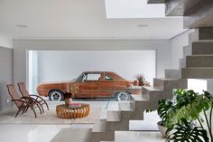 an orange car is parked in the middle of a room with stairs leading up to it