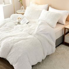 a bed with white comforters and pillows on top of it, next to a night stand