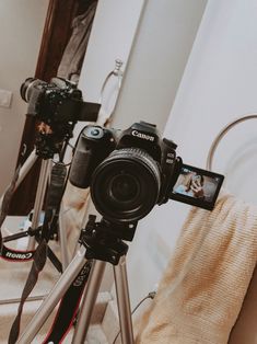 a camera sitting on top of a tripod in front of a mirror next to a towel