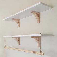 two white shelves with wooden brackets hanging from them