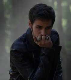 a man in a black leather jacket pointing his finger at the camera