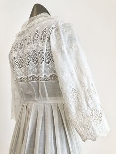 "Antique Edwardian white cotton lawn dress has eyelet lace embroidery throughout the bodice, sleeves, and around the hem. The dress has a ruffle trimmed net collar and net under bodice that has a crossover snap detail. The dress has snap and hook and eye closures at the skirt and bodice. Condition Overall excellent. There's a repair to the right sleeve, and orange stains near the seam. The front skirt has stains at the hem, the back skirt has some stains near the top of the lace, and yellowing a Classic Broderie Anglaise Dresses, White Cotton Lace Dress For Spring, Daywear Prairie Dress With Lace Trim, Spring Broderie Anglaise Cotton Lace Dress, Classic Broderie Anglaise Dresses For Daytime, Classic Broderie Anglaise Dresses For Daywear, Classic Dresses With Broderie Anglaise For Daywear, Elegant Cotton Victorian Dress For Spring, Broderie Anglaise Long Sleeve Day Dress