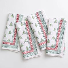 four white towels with red and green designs on them, one is folded to the side