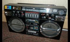 an old fashioned boombox with speakers on the floor next to a wall and carpet