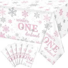 a table cloth with pink and silver snowflakes on it, next to five napkins