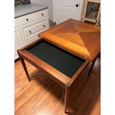 a wooden table with a black cloth underneath it on a hard wood floor in a kitchen