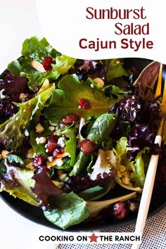 a salad with spinach and cranberries in a black bowl on top of a table