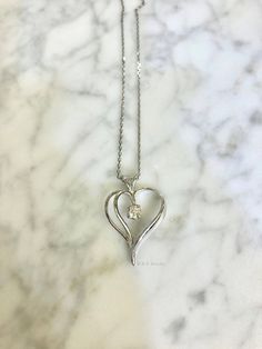 Metal: 14kt White Gold Stone: Diamond Stone Shape: Round Diamond Weight: .19 ctw Weight of Pendant with Diamond: 1.80 grams Dimensions Of Heart Including Bail: 26mm Long 18mm Wide Weight of Chain: 1.30 grams Type of Chain: 1mm Diamond Cut Cable Chain Type of Clasp: Spring Clasp Length of Necklace: 16 Inches. Other chains available. Customization: Can be custom made with any gems and metals. Formal Diamond Cut Heart Necklace In Diamond White, Classic Diamond Cut Necklace For Valentine's Day, Formal Diamond White Heart Necklace With Diamond Cut, Classic Round White Gold Heart Necklace, Formal Heart Necklace With Prong Setting For Valentine's Day, Formal Heart Cut Necklace With Prong Setting, Formal Diamond Cut Heart Necklace, White Gold Double Heart Jewelry With Prong Setting, Double Heart Diamond Ring With Prong Setting