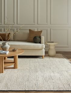 a living room with a couch, coffee table and vase on top of the rug