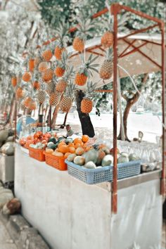 an outdoor fruit stand with pineapples and oranges