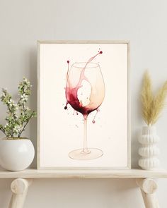 a wine glass with red liquid in it sitting on top of a shelf next to a vase