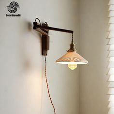 an old fashioned wall light hanging from the side of a white wall next to a window