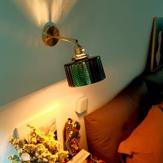 a lamp that is on in the corner of a room next to a pillow and flowers