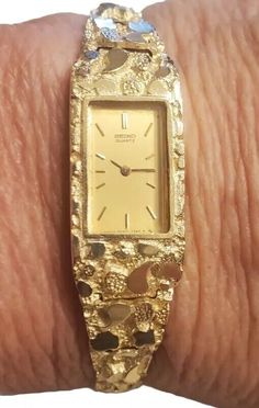 This vintage Seiko wristwatch is a stunning piece of luxury for women. The watch features a polished yellow gold case with a hidden fold clasp closure and a two-piece strap with a maximum wrist size of 6.26-6.75 inches. The cushion-shaped watch face is set with a beautiful gold bezel, and the watch is water-resistant. The watch has a quartz movement and a 12-hour dial, with an unknown number of jewels and year of manufacture. It comes with its original box and packaging, and is a rare find for collectors. The watch has a fixed bezel type and a solid caseback. It is a perfect addition to any dress/formal outfit and is sure to catch the eye of admirers. Bracelet Watches Women Vintage Style, Gold Rectangular Jewelry For Anniversary, Collectible Gold Watch With Rectangular Dial, Gold Rectangular Watch With Box Clasp, Gold Jewelry And Watches With Polished Finish For Weddings, Gold Polished Finish Jewelry And Watches For Wedding, Wedding Jewelry And Watches In Gold With Polished Finish, Gold Wedding Jewelry And Watches With Polished Finish, Elegant Gold Engraved Watches