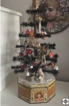 a small christmas tree with angel figurines and ornaments on it's top