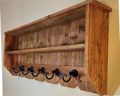 a wooden shelf with four hooks on it