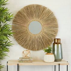 a round mirror sitting on top of a wooden table next to a potted plant