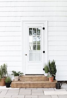 a white front door with potted plants on the steps