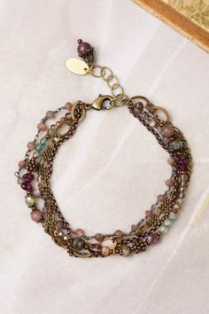 A stylish multistrand design, handcrafted with collage strands for a unique look. Antique Brass (lead and nickel free) Crystal, Lepidolite Quartz, Czech Glass 7.5-8.5", adjustable with an antique brass lobster claw clasp We hand select our natural materials, thus there may be slight variations in color and/or size that will not detract from the overall aesthetic Our unique handcrafted designer jewelry for women is made in America, with each design created individually in our personal design studio in Floyd VA USA Bohemian Bracelets With Extender, Bohemian Adjustable Bracelets With Extender, Bohemian Brass Bracelets With Adjustable Chain, Bohemian Metal Beaded Bracelets With Adjustable Chain, Bohemian Bracelets With Adjustable Chain, Bohemian Multi-strand Nickel-free Bracelets, Bohemian Multi-strand Wire Wrapped Beaded Bracelets, Bohemian Multi-strand Nickel Free Bracelets, Nickel Free Multi-strand Bracelets For Jewelry Making