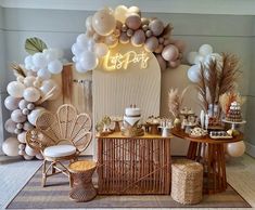 a table topped with lots of balloons next to a chair and other items in front of a wall