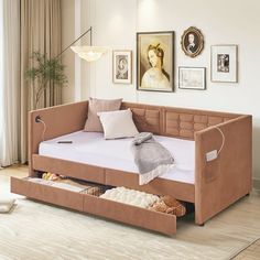 a day bed with storage underneath it in a room next to a window and pictures on the wall