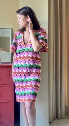 a woman is standing in front of a mirror wearing a colorful crochet dress