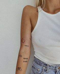 a woman with a small tattoo on her arm and hand is standing in front of a white wall