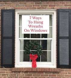 there is a wreath on the window sill with red ribbon tied around it and black shutters