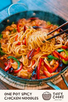 one pot spicy chicken noodles with chopsticks in a wok on a wooden table