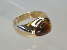 Central to this Vintage ring is a smooth, triangular shaped Tigers Eye stone, it catches the light beautifully, changing in tone from deep brown to golden yellow, giving this ring a warm colour palette.  This ring is available in sizes L1/2 and M.  The ring is stamped; 9K 375 EG&A SC. The ring is hallmarked; 375, the London Assay Office import mark, and the letter 'C' which suggests it was hallmarked in 1977. Luxury Brown Formal Rings, Fine Jewelry 14k Gold Brown Ring, Classic 14k Gold Brown Ring, Brown 14k Gold Fine Jewelry Ring, Brown 14k Gold Rings Fine Jewelry, Classic Brown Signet Ring For Anniversary, Classic Brown Jewelry For Formal Occasions, Classic Brown Jewelry For Formal Events, Brown Gemstone Rings In 14k Gold