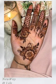 a woman's hand with henna tattoos on it and flowers in the background