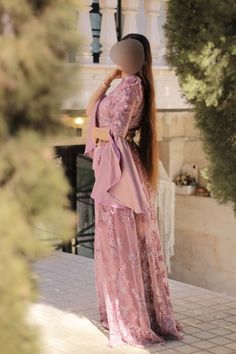 a mannequin wearing a pink dress and headdress in front of a building