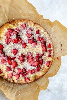 a cake with powdered sugar and strawberries is on top of some brown paper