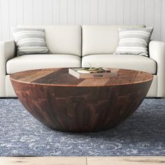 a large wooden table sitting on top of a blue rug in front of a white couch