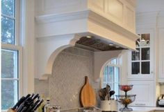 a kitchen with white cabinets and an island in front of the stove top is filled with cooking utensils