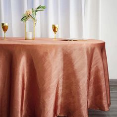 the table is set with two glasses and a gold candle holder on top of it