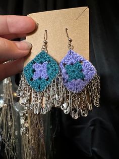 a pair of crocheted earrings is being held up by someone's hand