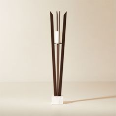 a tall white and brown vase with two sticks sticking out of it's sides