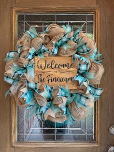 a welcome to the family wreath hanging on a door with a glass window behind it