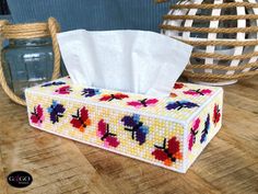 a tissue dispenser sitting on top of a wooden table next to a basket