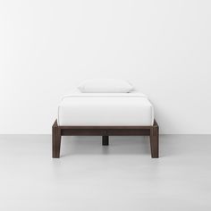 a bed sitting on top of a white floor next to a wall