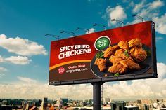 a billboard advertising fried chicken on the top of a building in an urban area with blue sky and clouds