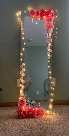 a mirror that has some lights on it and flowers in front of it, with the reflection